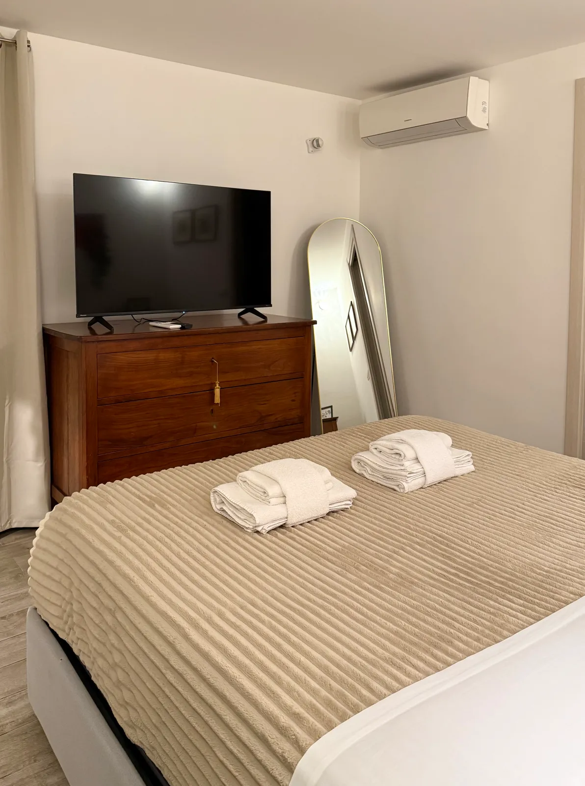 Comò antico in legno con la TV, di fronte al letto