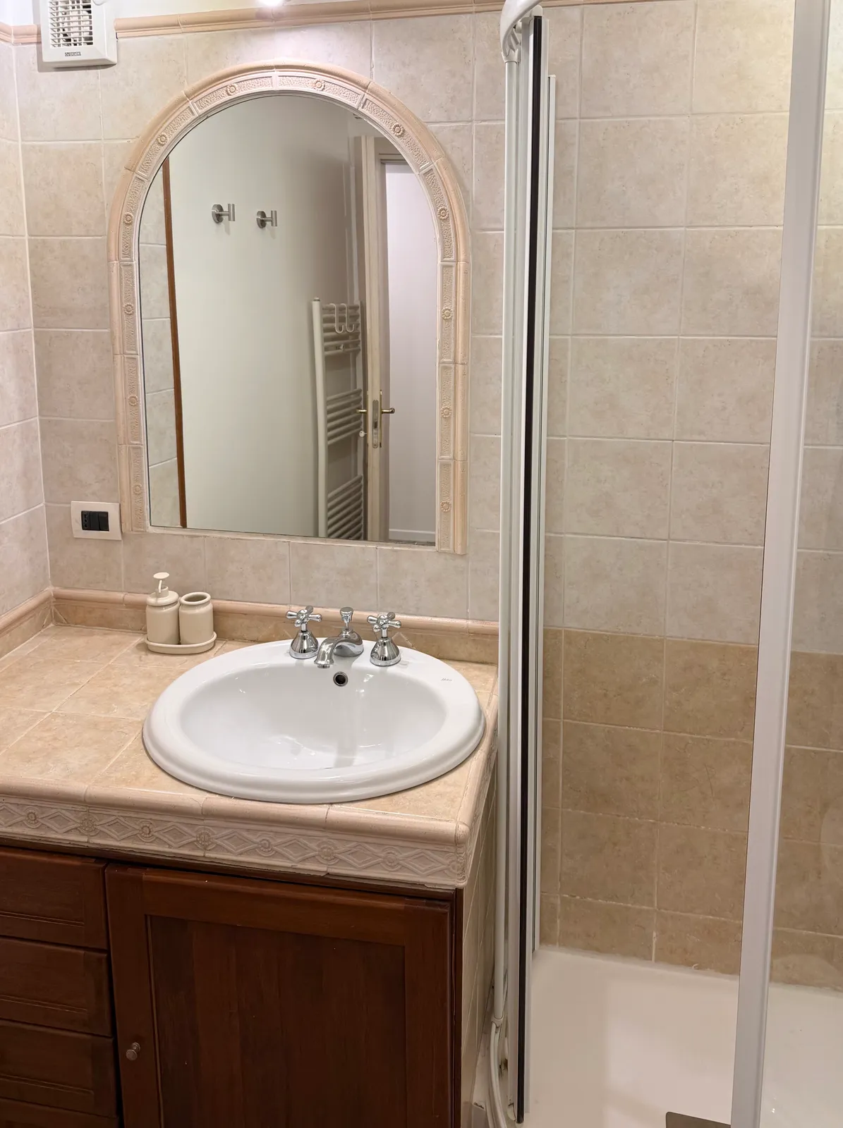 Il lavabo del bagno della camera 1 con il mobile in noce e lo specchio ad arco