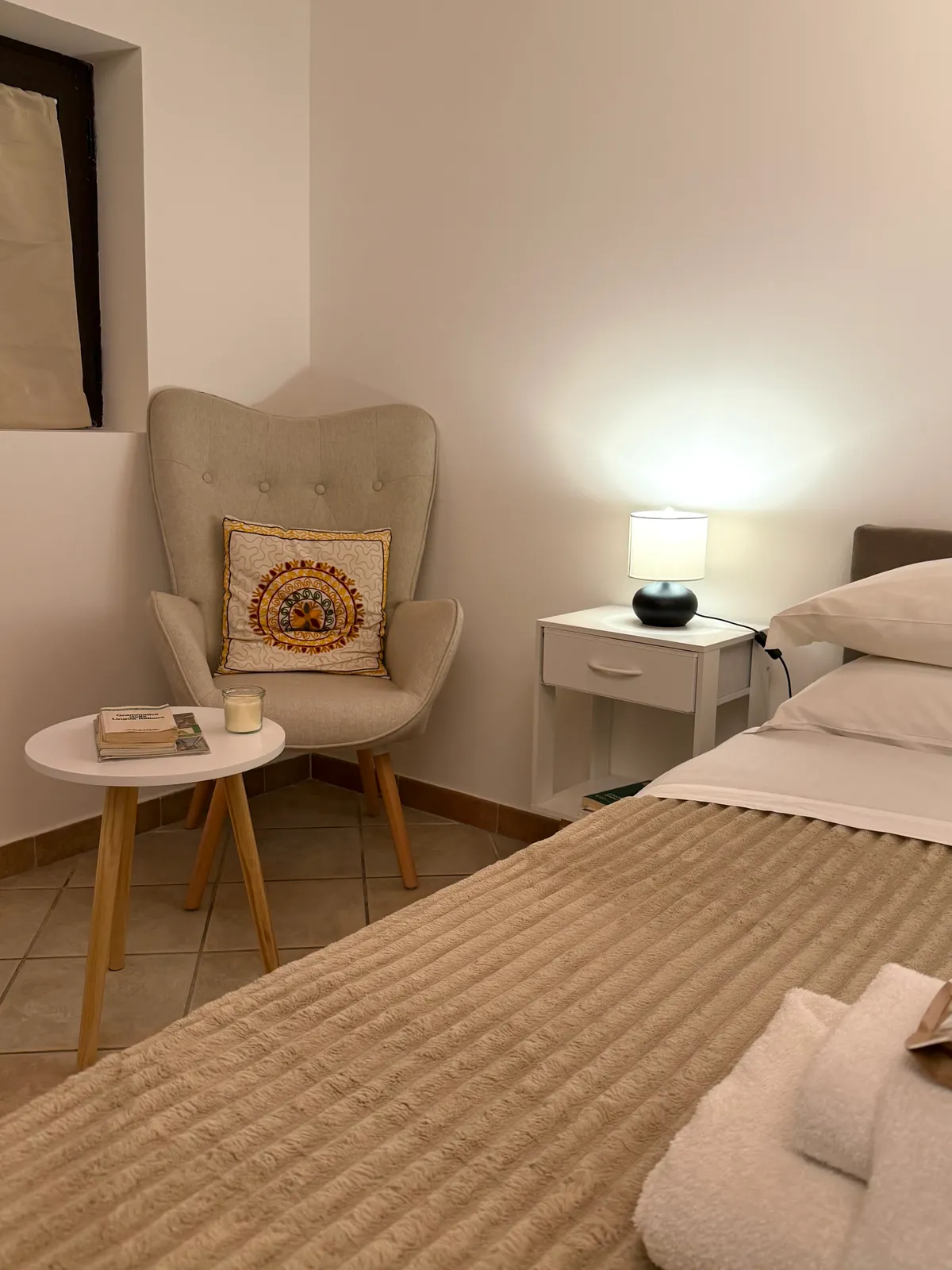 La poltrona e il comodino con la lampada, accanto al letto