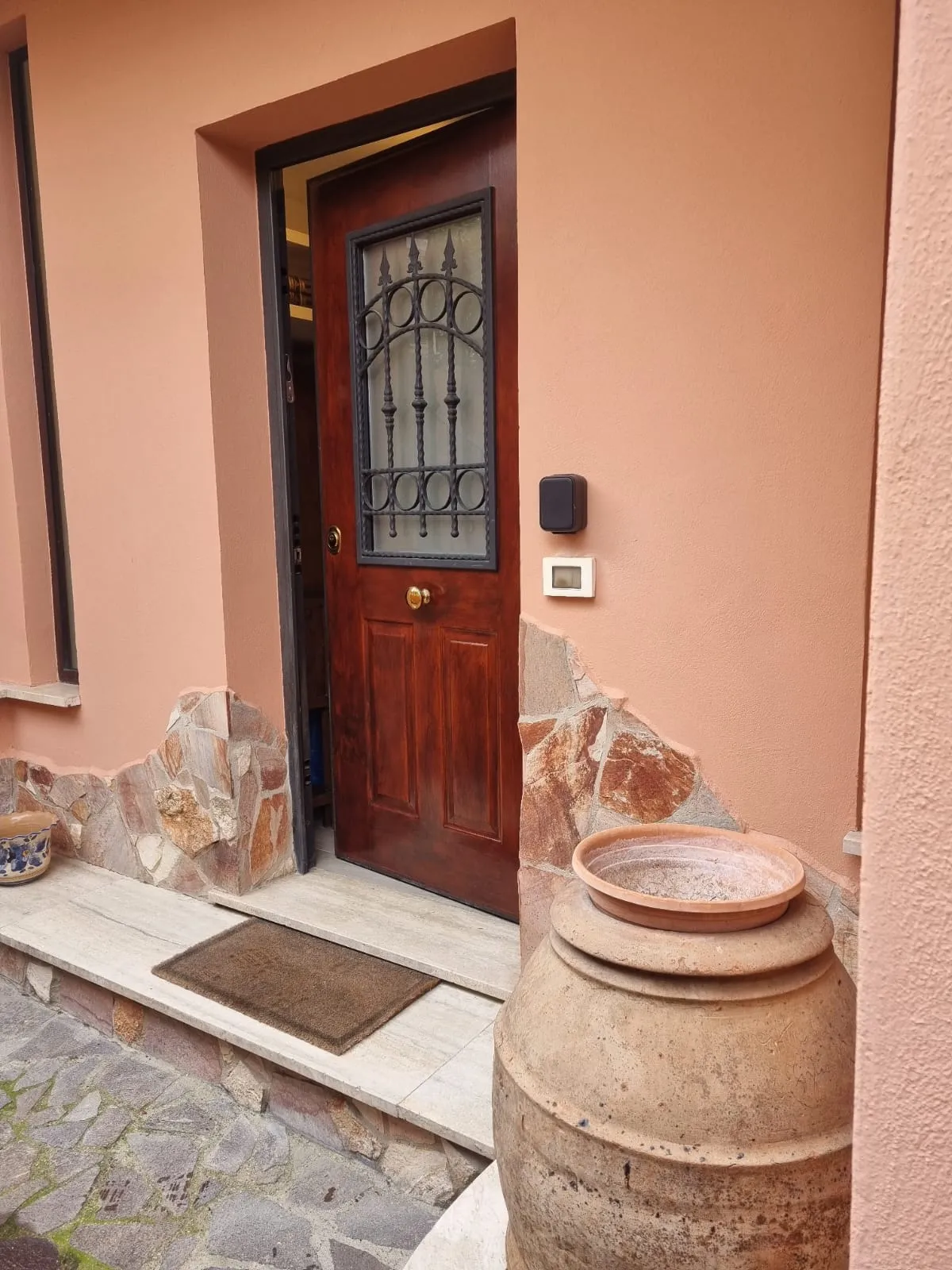 La porta di casa in legno con la vetrata decorata e il tastierino