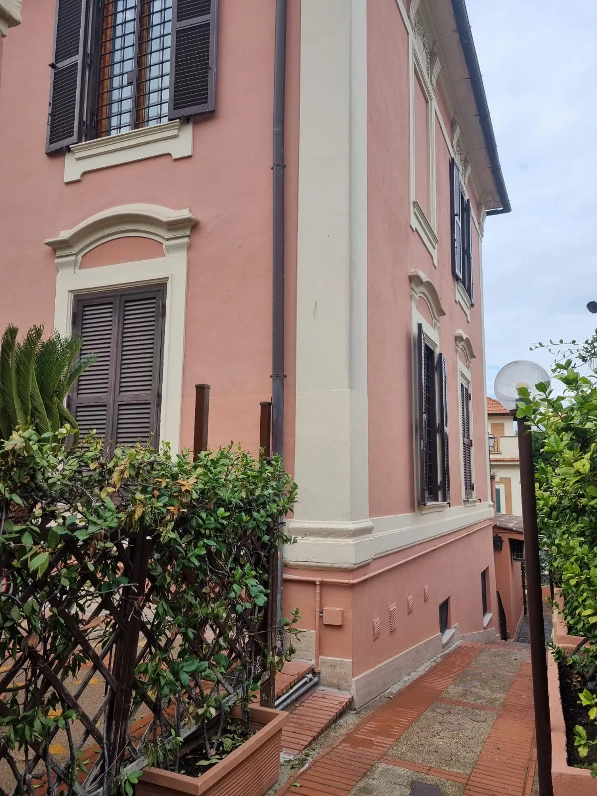 Il vialetto lungo il fianco rosa del villino, tra le piante